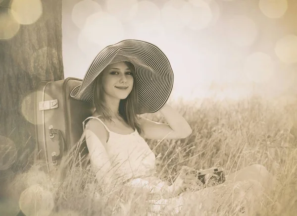 Vrouw in de hoed zit in de buurt van boom — Stockfoto