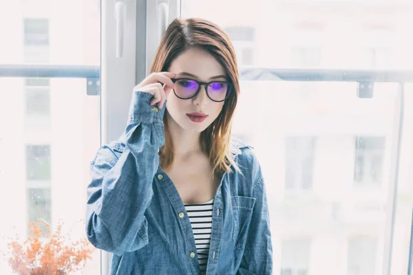 Junge Frau mit Brille am Fenster — Stockfoto