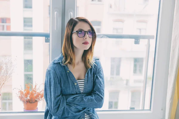Junge Frau mit Brille am Fenster — Stockfoto