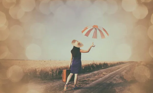 Девушка с чемоданом и зонтиком — стоковое фото