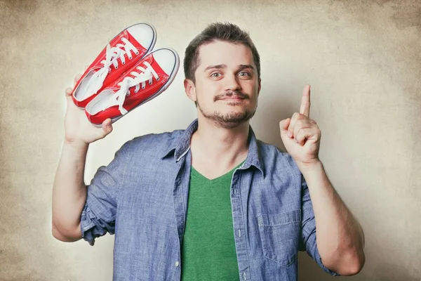Hombre sosteniendo zapatos de goma rojos — Foto de Stock