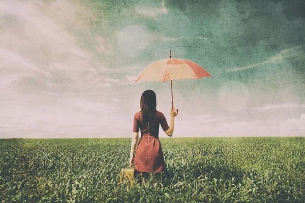 Ung kvinna med resväska och paraply — Stockfoto