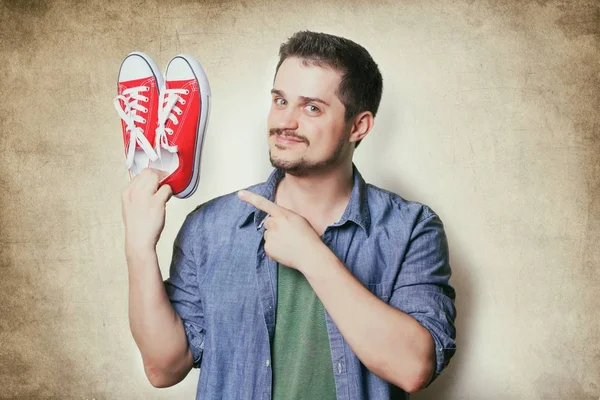 Hombre sosteniendo zapatos de goma rojos —  Fotos de Stock