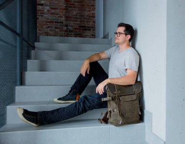 Sırt çantası merdiven oturan adam. 