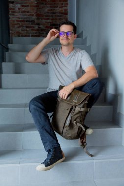 Sırt çantası merdiven oturan adam. 