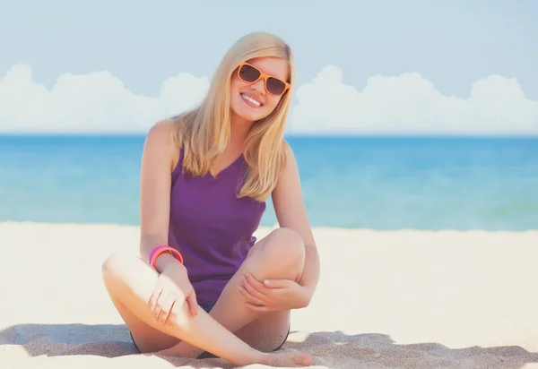 Chica rubia sentada en la playa — Foto de Stock