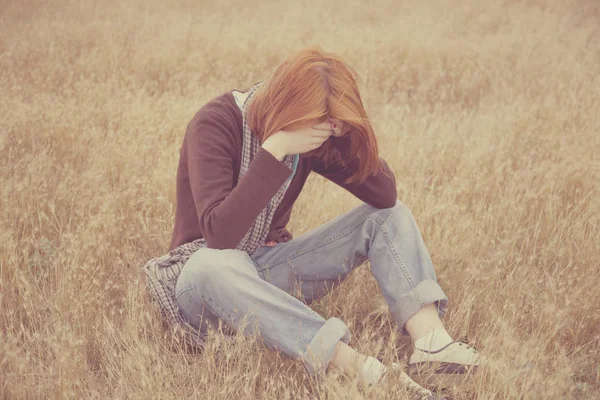 Ragazza rossa seduta sul campo — Foto Stock