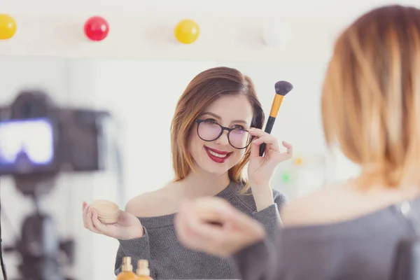 Vrouw toepassen van cosmetica op camera — Stockfoto