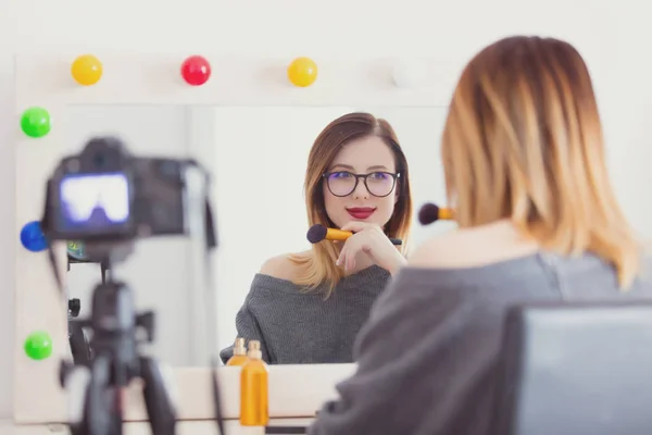 Vrouw toepassen van cosmetica op camera — Stockfoto