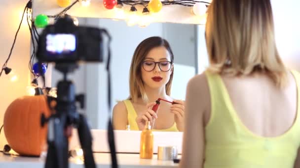 Vrouw toepassen van cosmetica op camera — Stockvideo