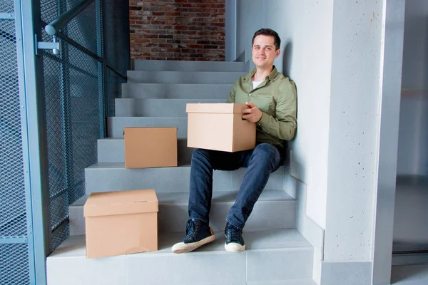 Hareketli Kutular ile merdivenlerde oturan adam — Stok fotoğraf
