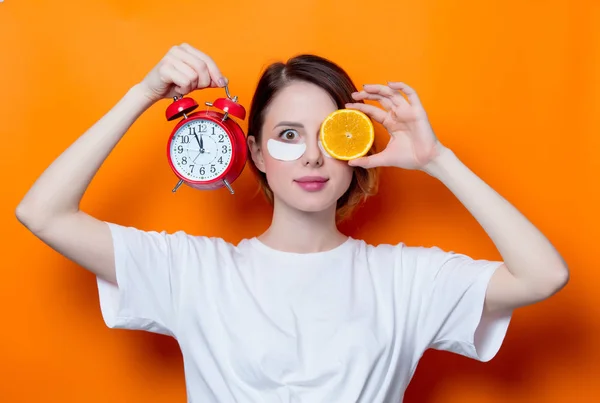 Femme avec tranche d'orange et réveil — Photo