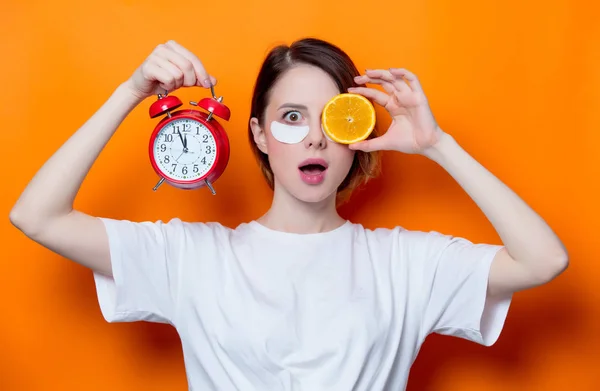 Woman with orange slice and alarm clock — Stock Photo, Image