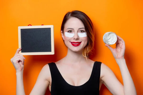 Mulher segurando creme rosto e quadro — Fotografia de Stock