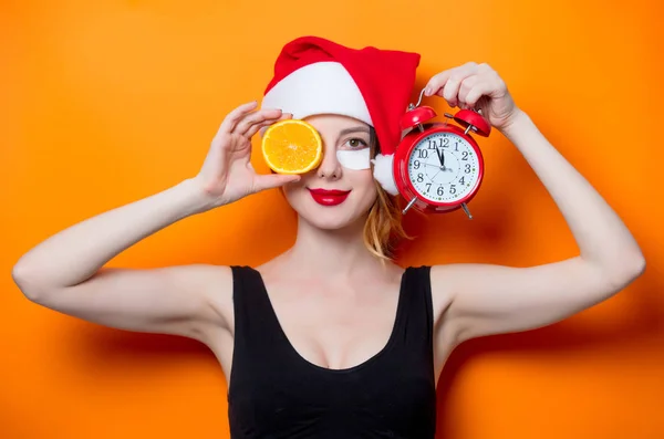 Mujer con rebanada naranja y despertador — Foto de Stock