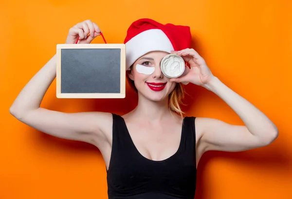 Mujer sosteniendo crema facial y pizarra — Foto de Stock