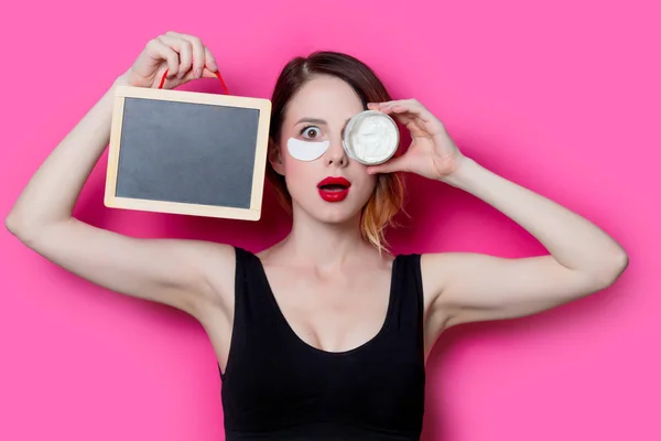 Mulher segurando creme rosto e quadro — Fotografia de Stock