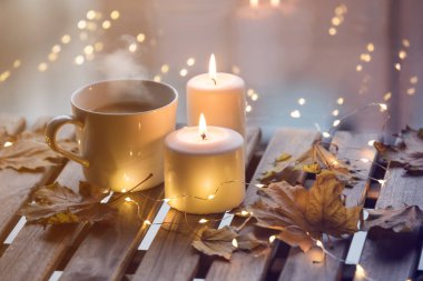 fincan kahve ve masanın üzerinde duran mum