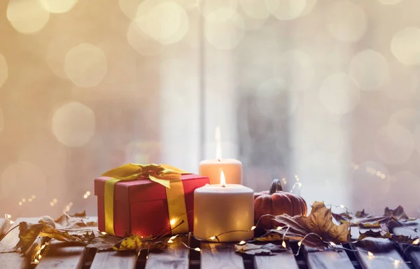 Pumpkin, gift and candles with maple leaves — Stock Photo, Image