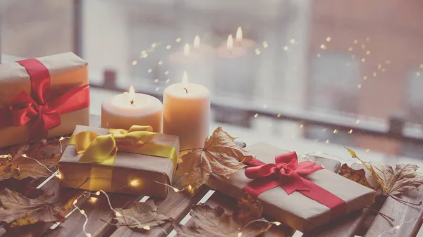 Geschenken en kaarsen met esdoorn bladeren op tafel — Stockfoto