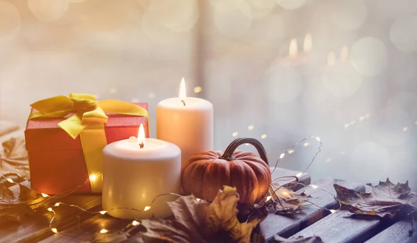 Pumpkin, gift and candles with maple leaves — Stock Photo, Image