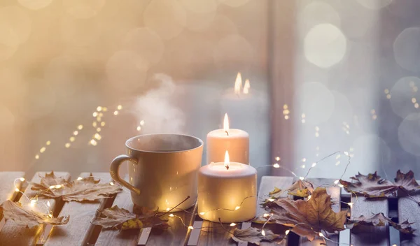 Xícara de café e velas em pé na mesa — Fotografia de Stock