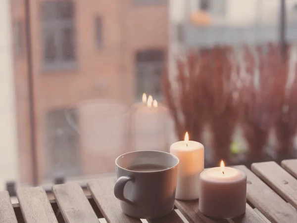 Taza de café y velas de pie sobre la mesa —  Fotos de Stock