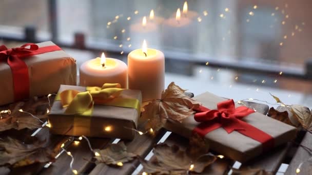 Geschenken en kaarsen met esdoorn bladeren op tafel — Stockvideo