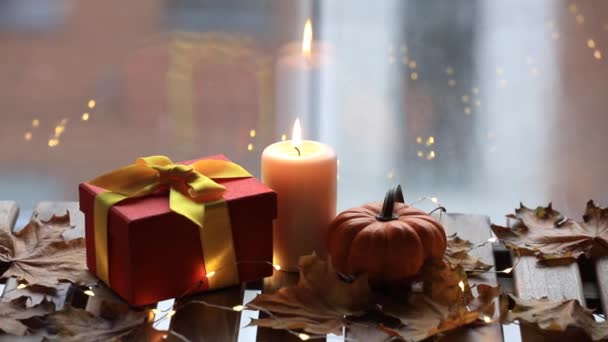 Тыква, подарок и свеча стоят на столе — стоковое видео