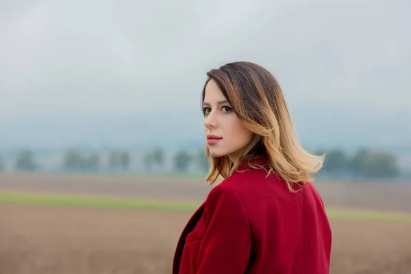 Рыжая женщина в красном пальто в сельской местности — стоковое фото