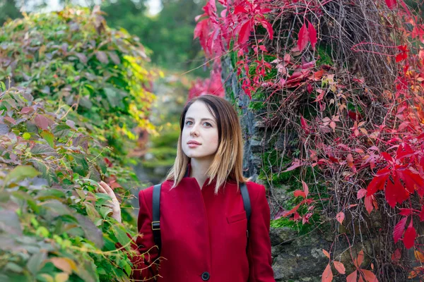 Roodharige vrouw met rugzak in tuin — Stockfoto