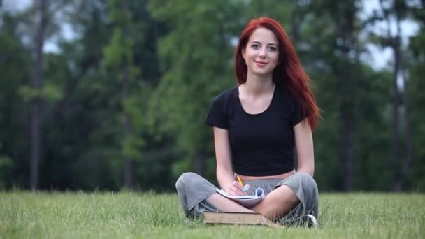 Ruda kobieta z notebooka na trawie. — Wideo stockowe