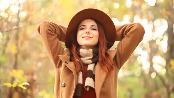 Рыжая женщина в шляпе в осеннем парке — стоковое видео
