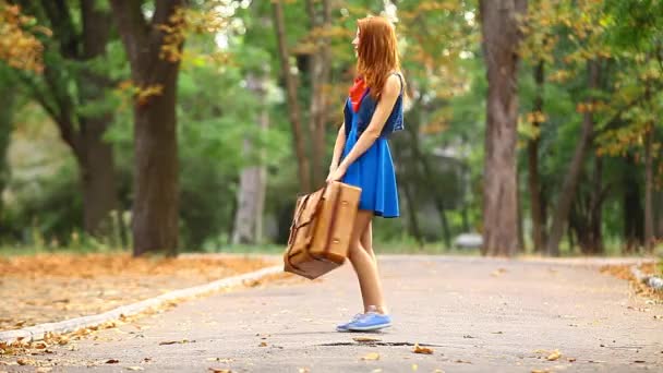 Vrouw in blauwe jurk met koffer — Stockvideo