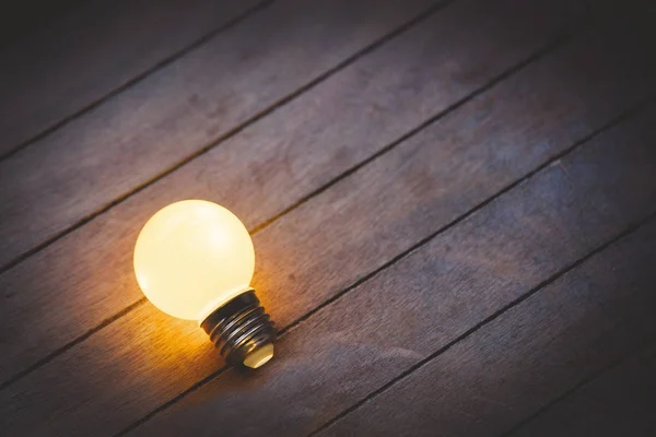 Luz en la bombilla sobre fondo de madera . —  Fotos de Stock