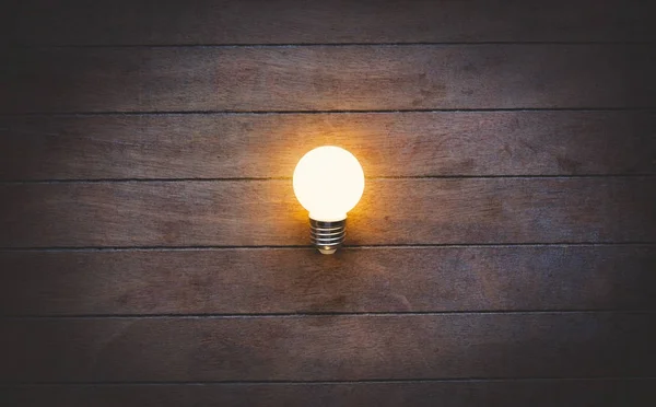 Luz en la bombilla sobre fondo de madera . — Foto de Stock