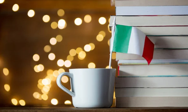 Weiße Tasse mit Fahne in der Nähe von Büchern — Stockfoto