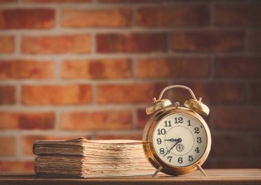 Vintage çalar saat ve ahşap masa üzerinde eski kitaplar 