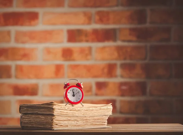 ビンテージの目覚まし時計と木製のテーブル上の古い本 — ストック写真