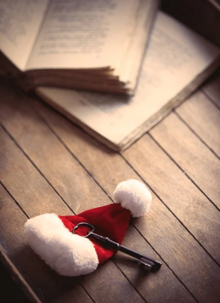 Santa Claus Christmas hat with classic key and old books — Stock Photo, Image