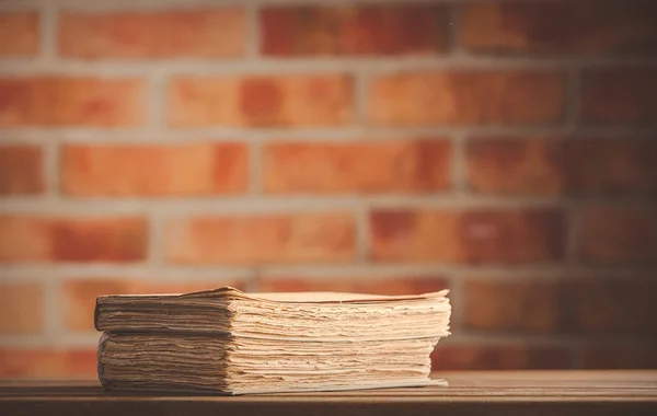 Libros antiguos sobre mesa de madera en la pared de ladrillo —  Fotos de Stock