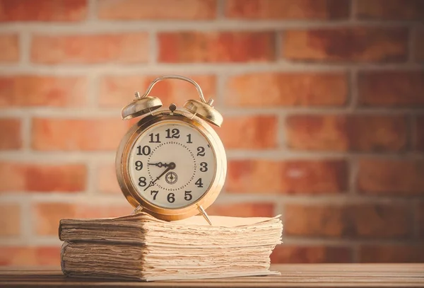 Reloj despertador vintage y libros antiguos sobre mesa de madera —  Fotos de Stock