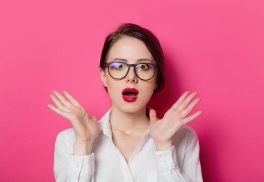 Genç sürpriz iş kadını pembe bir arka plan üzerinde gözlük portresi. 