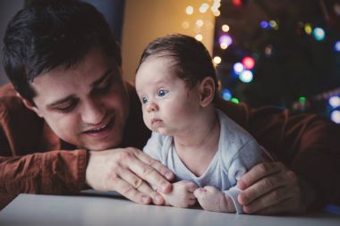 Genç yardım için bir küçük çocuk yalan karın üzerinde ilk kez baba. Bebek odaklı kapalı görüntü