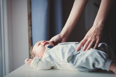 Bir pencere yakınında beyaz masada küçük bebek ve anne fotoğrafı eller. Doğal gün ışığı ile yapılmış resim.