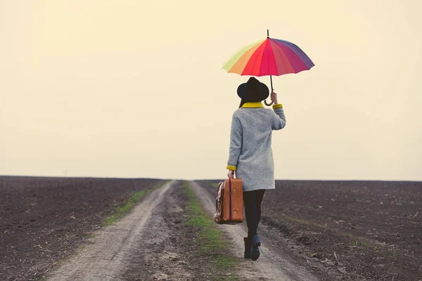 Jonge vrouw met paraplu en koffer — Stockfoto