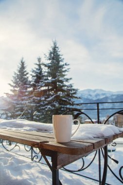 Ahşap masa üzerinde içkiyle Dağları arka plan üzerinde beyaz fincan. Polonya, Zakopane