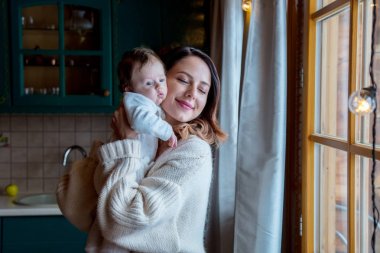 Genç anne kazak holding çocuk kapalı mutfak at