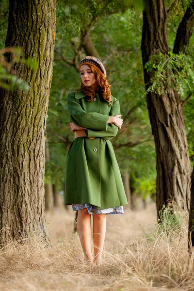 portrait of young woman in green coat at countryside outdoor