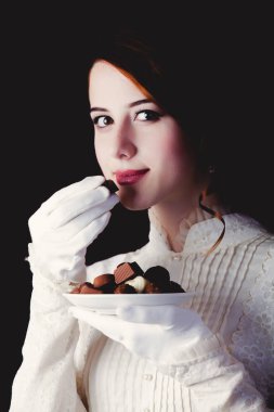 Siyah arka plan üzerine şeker ile beyaz Victoria dönemi giysili genç Kızıl saçlı kadın.